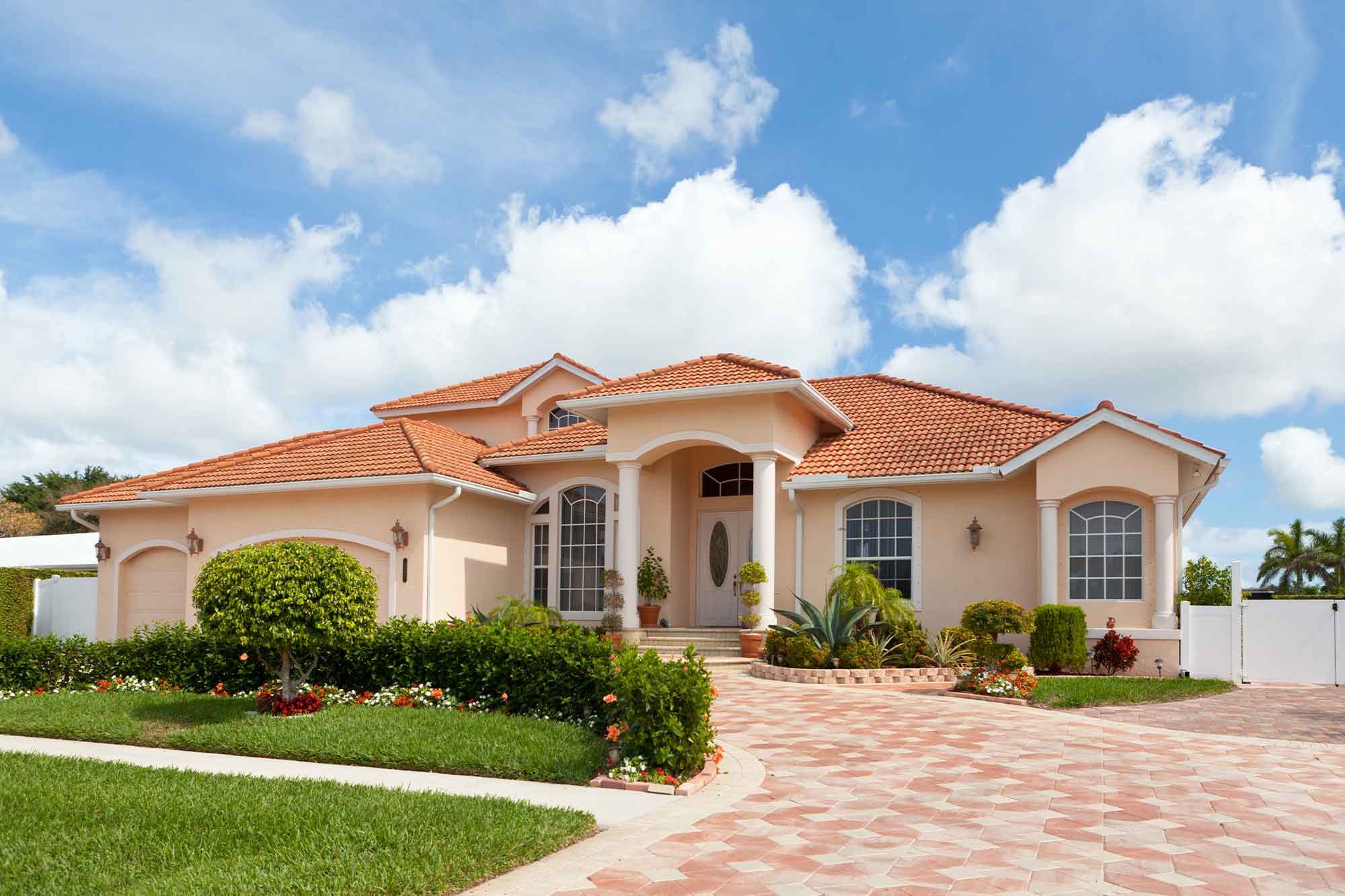 A beautiful Florida home with a green lawn, paved driveway, and blue sky.