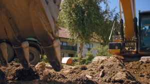 Photograph of excavator machine digging the ground for septic tank installation.