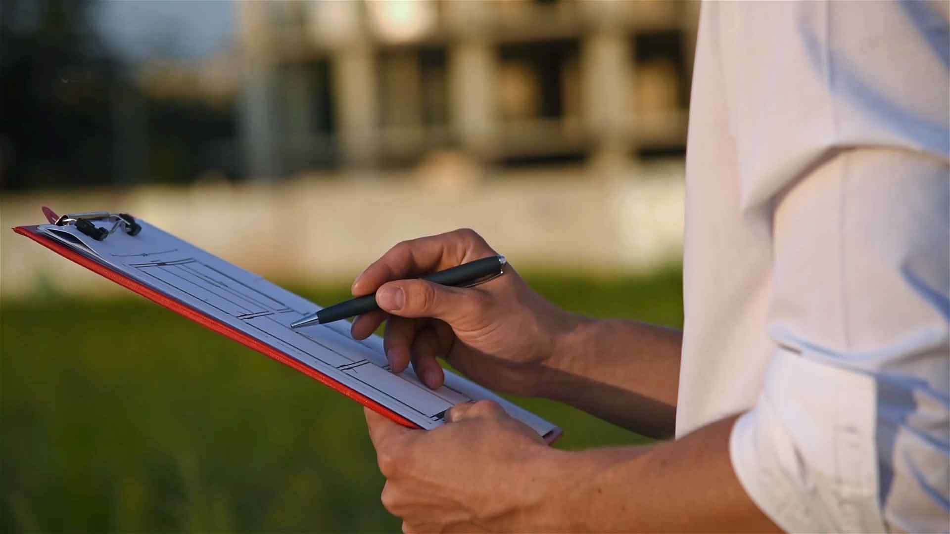 Image of septic tank inspector holding a clipboard, in front of a home.