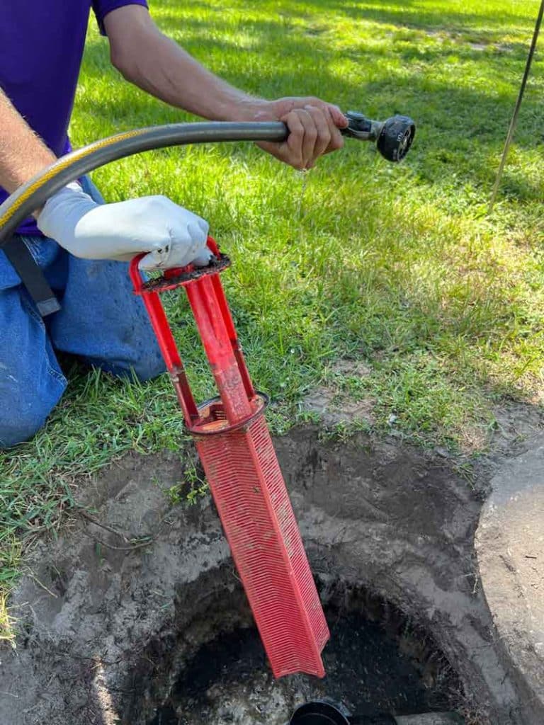 A person holding a garden hose and a washed septic filter.