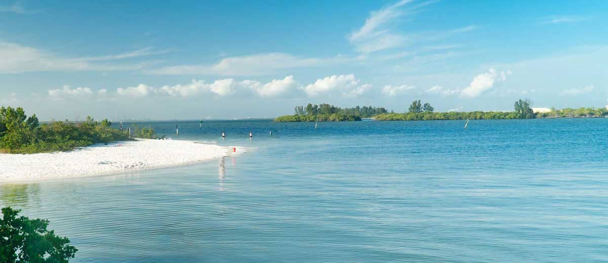 Photo of a blue sky with white sand beach and clear water.