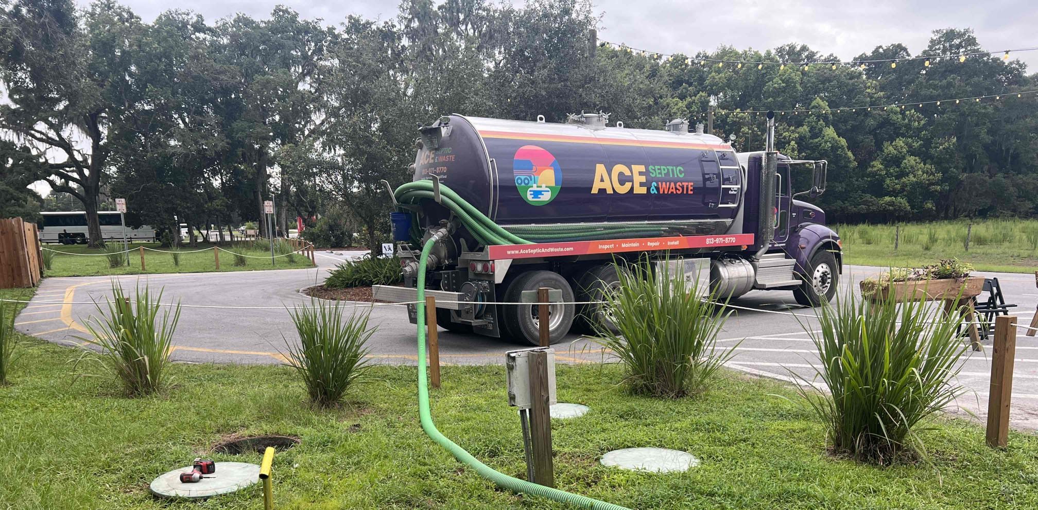 An ACE Septic-branded septic truck next to a septic tank with a long hose leading off-screen.