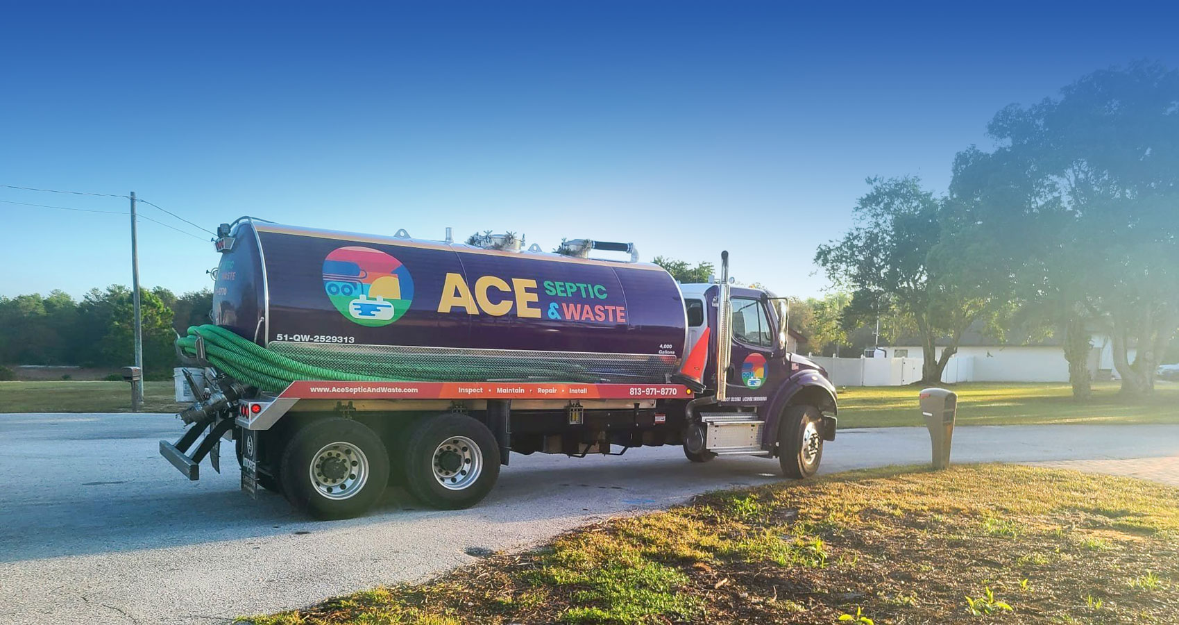 A purple septic truck with the logo ACE Septic & Waste on a street with a blue sky in the background.