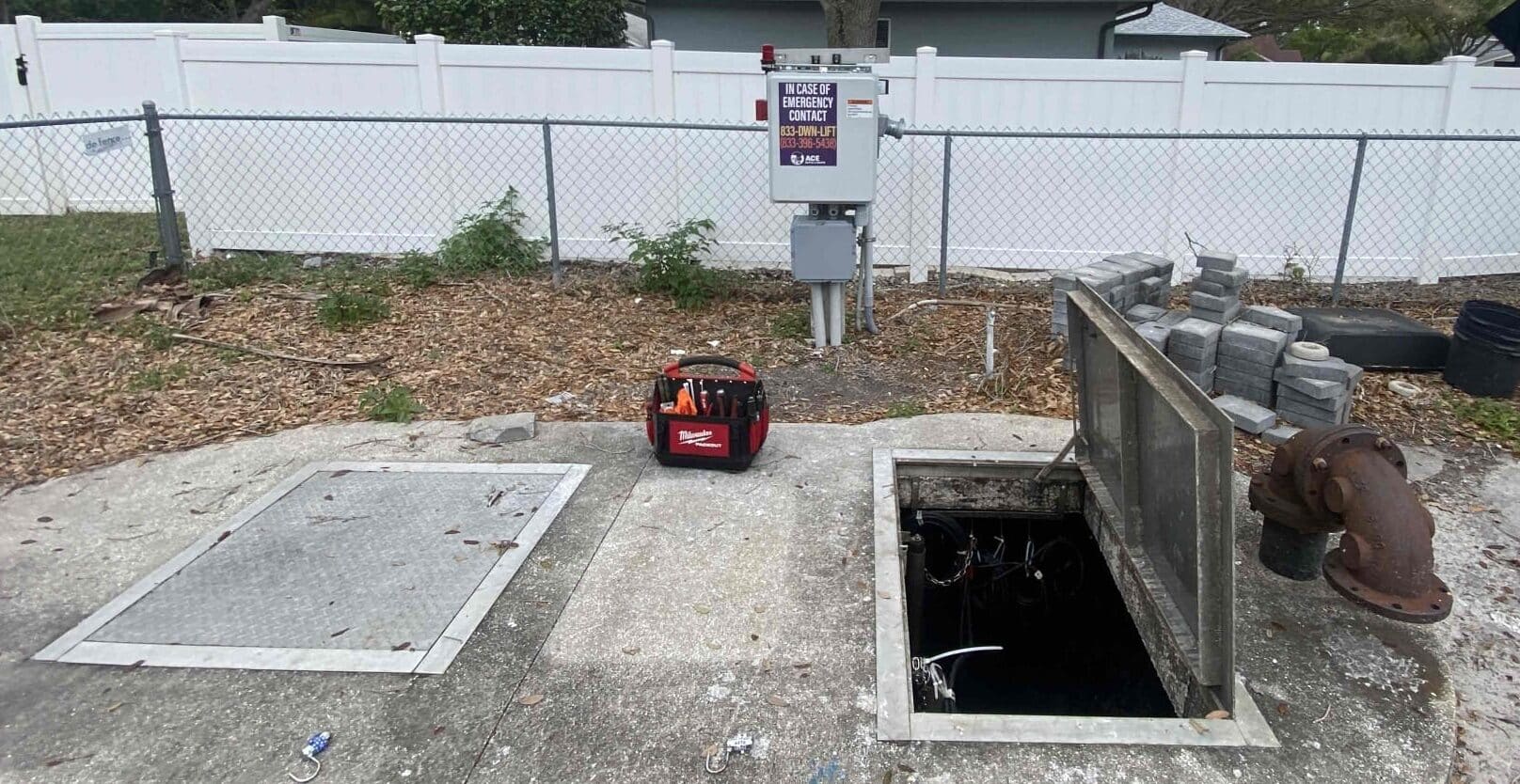 A lift station and control panel during an inspection with an exposed hatch.