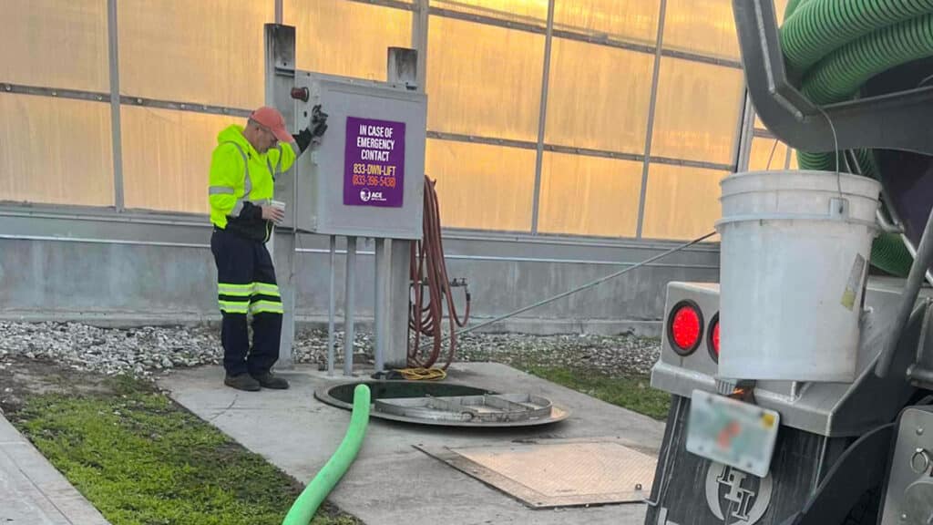 A man watching a lift station be pumped with a septic truck.