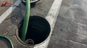 A grease trap in a parking lot in the process of being pumped.